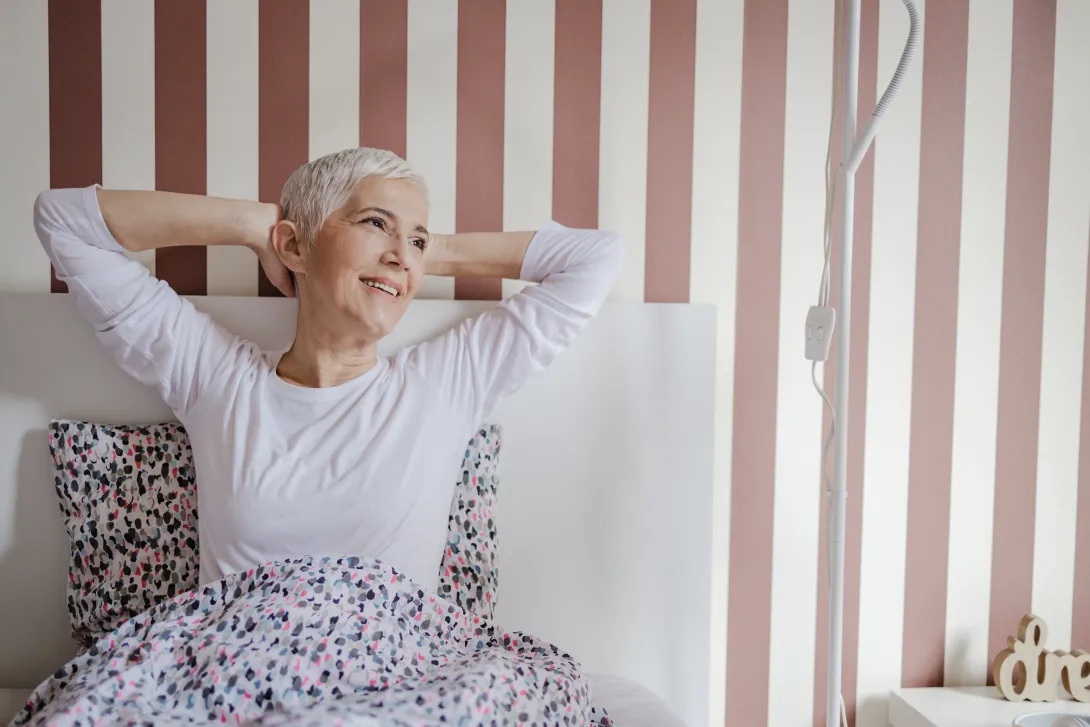 Una hermosa mujer mayor con cabello corto y gris en la cama en pijama por la mañana.