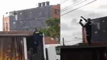 Ante la falta de escalera, el policía pide ayuda a un conductor para treparse sobre su vehículo.