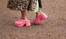 Se ve a una invitada con un abrigo con estampado de leopardo, un vestido teñido anudado verde neón, un bolso rosa de Bottega Veneta y sandalias rosas Balenciaga x Crocs fuera del espectáculo Opera Sport durante la Semana de la Moda de Copenhague