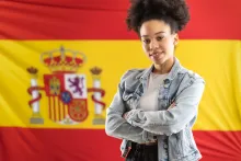 Joven con los brazos cruzados frente a la bandera española.