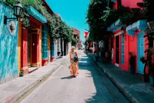 Mujer joven caminando por una calle colorida en la ciudad vieja de Cartagena, Colombia