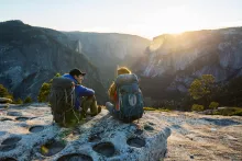 Una pareja sentada en una repisa mientras viajaba con mochila en el valle de Yosemite.