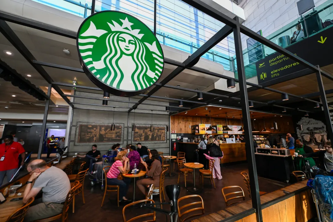 Los clientes se sientan en el café Starbucks en la sala de llegadas de la Terminal 1 del Aeropuerto Internacional Humberto Delgado el 2 de agosto de 2024