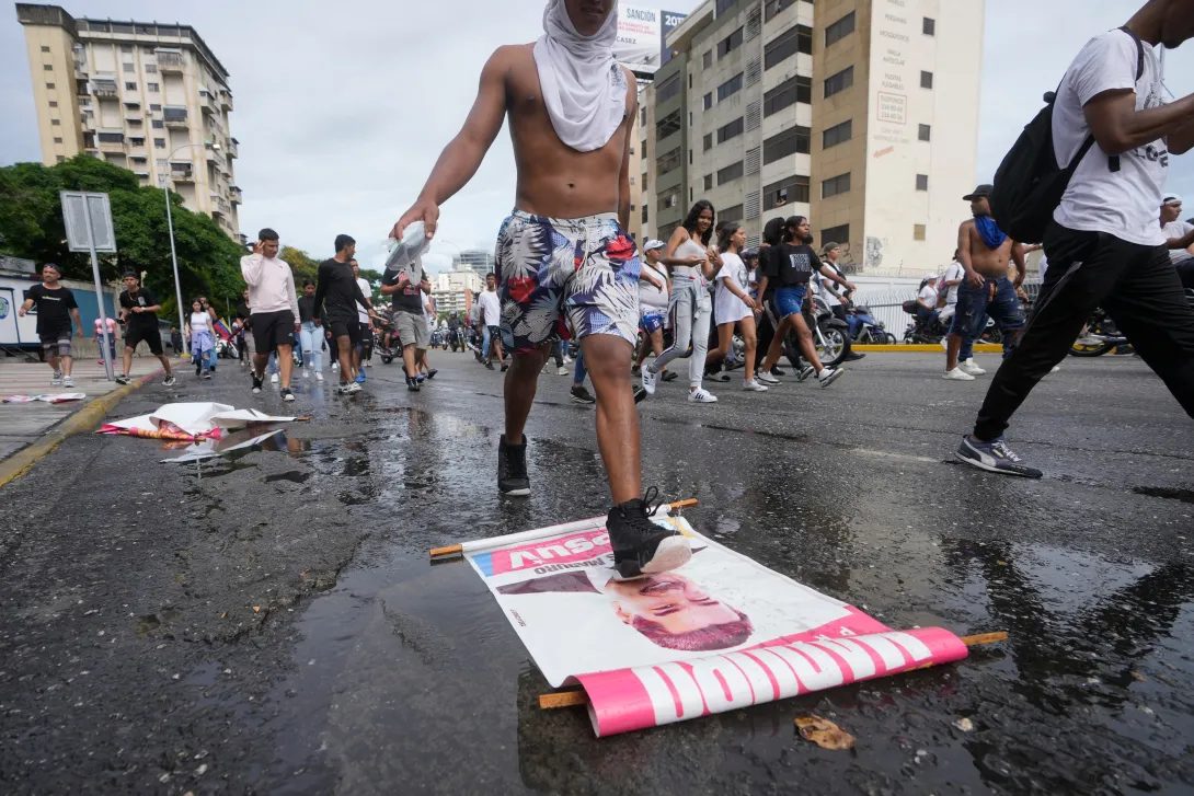 A protester steps on a campaign sign of President Nicolas Maduro during a march against hish being declared the winner of the presidential election, the day after the vote in Caracas, Venezuela, Monday, July 29, 2024. (AP Photo/Fernando Vergara)