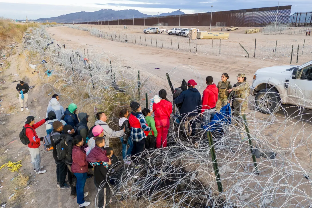 Visto desde una vista aérea, las tropas de la Guardia Nacional de Texas detienen a los inmigrantes que intentan pasar a través de alambre de púas después de cruzar la frontera hacia El Paso, Texas desde El Paso, Texas.