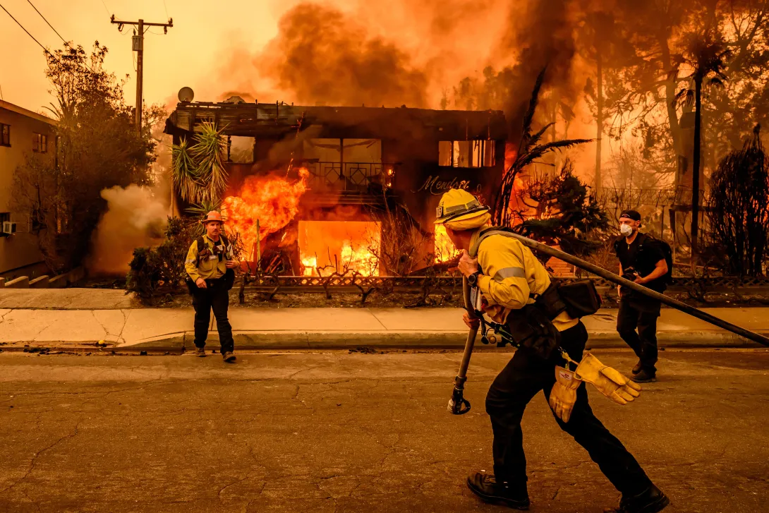 Bomberos en Los Ángeles atendiendo un incendio en una zona residencial.